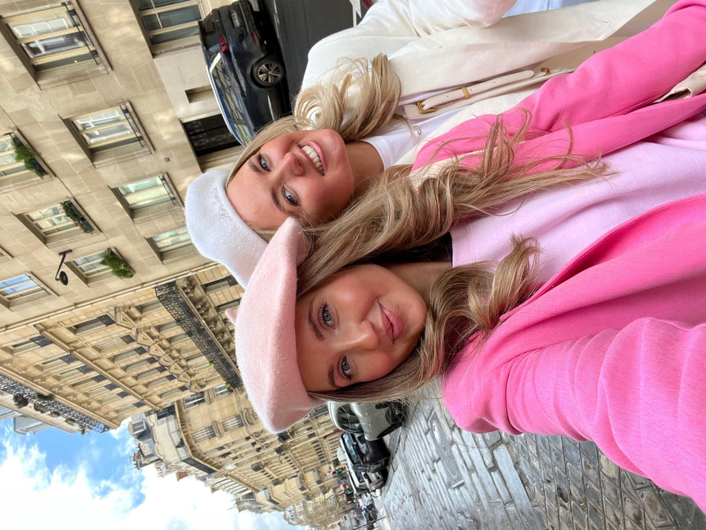 Two women posing for a photo with a cityscape background
