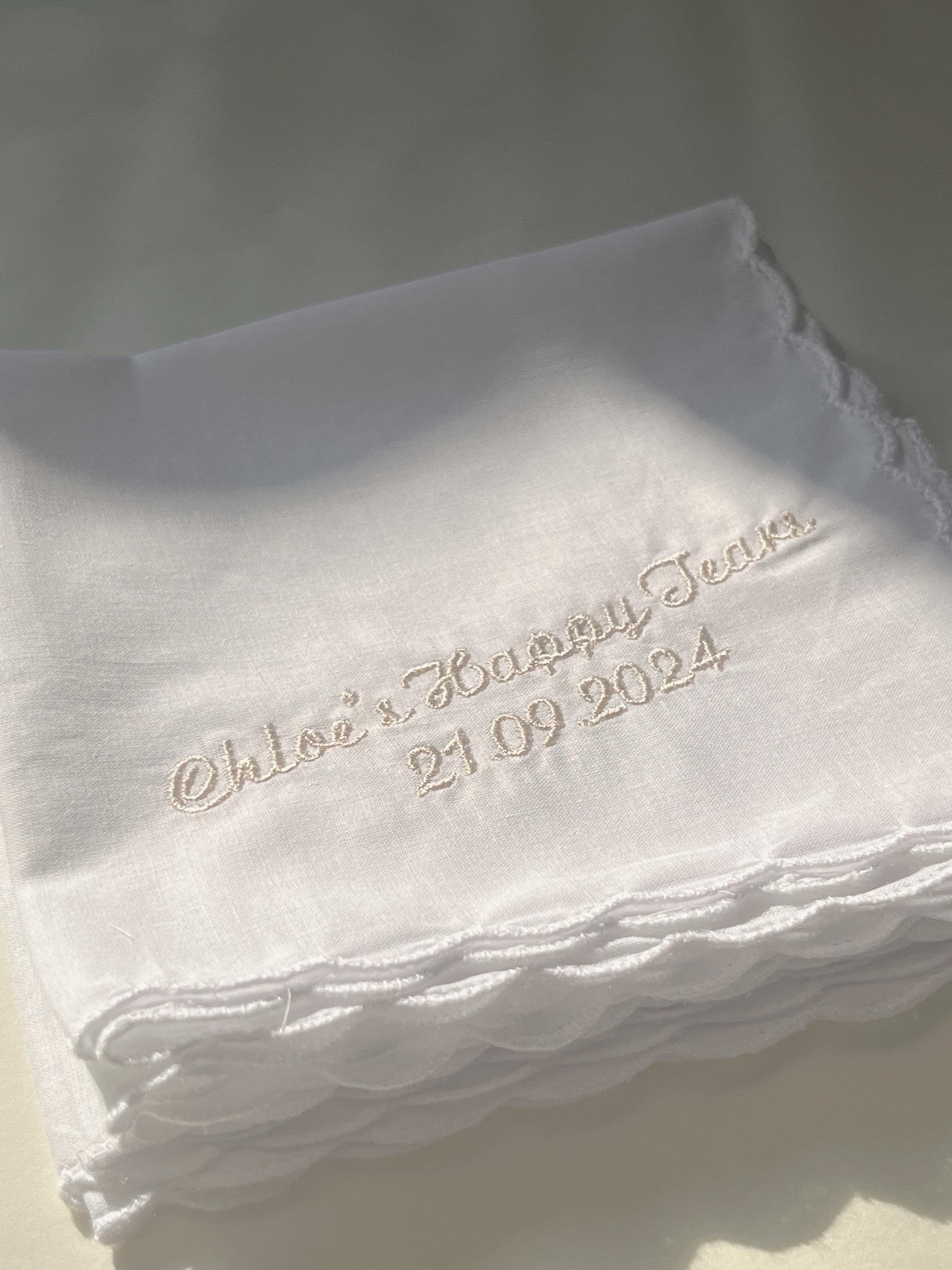 Stack of white handkerchiefs with embroidered text on a light background