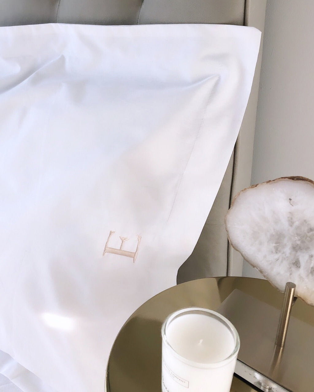 White pillow with a beige letter 'E' on a neutral background