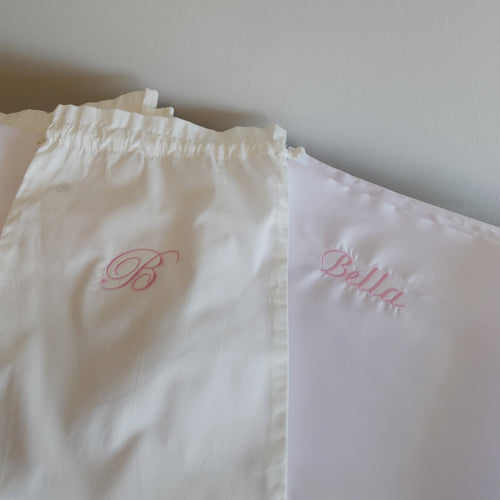 one white pillow with 'Bella' embroidered on them against a plain background.